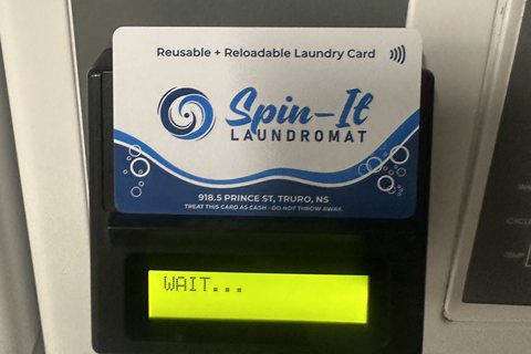 Spin-It laundry card held on a washer's card reader