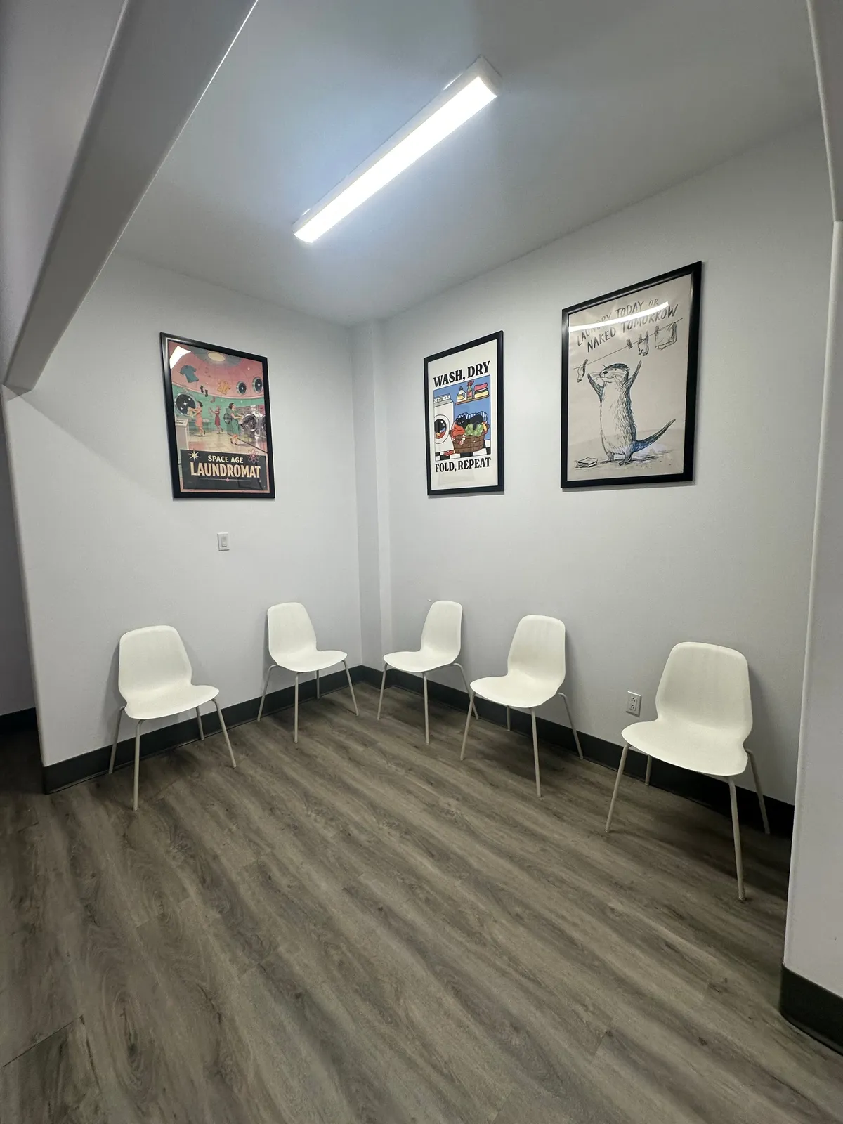 Comfortable seating in the Spin-It Laundromat waiting area with framed artwork